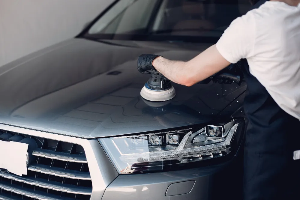 A person removing swirl marks from the car with a buffer