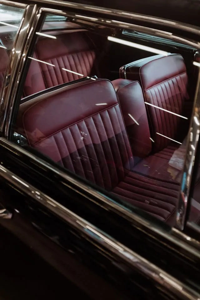 Interior view of a classic car with maroon leather seats, emphasizing well-maintained upholstery free from coffee, juice, and grease stains