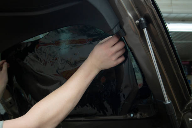 Technician applying car window tint film with precision during professional installation in Sharjah
