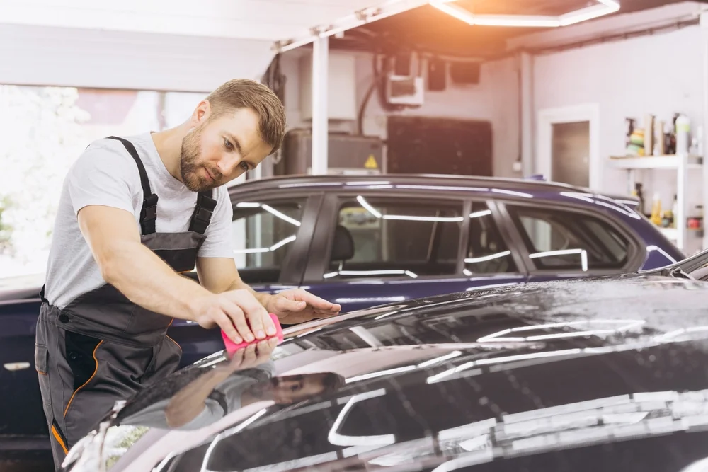 Professional detailing worder installing car paint protection sheet