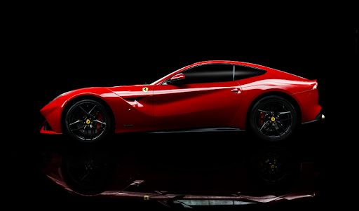 Red sports car in profile on a dark reflective floor, showing well-maintained paintwork and clean alloy wheels